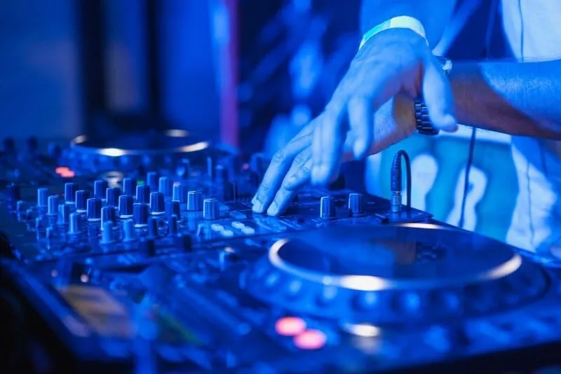 DJ playing music at a mixer under colorful lights